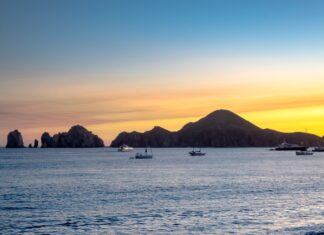 Sunset over the ocean in Cabo San Lucas with sailboats in the water