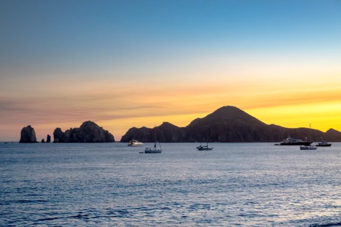 Sunset over the ocean in Cabo San Lucas with sailboats in the water