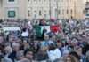 A crowd in St. Peter's Square watching the first public address of Robert Prevost as Pope Leo XIV. Above their shoulders, an exuberant Mexican man holds a Mexican flag in front of his chest as he watches.