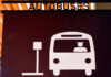 A sign in Puerto Vallarta indicating a bus hub with a icon of a man driving a bus pulling up to a bus stop sign and the word "Autobuses" on top of the sign.