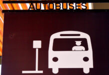 A sign in Puerto Vallarta indicating a bus hub with a icon of a man driving a bus pulling up to a bus stop sign and the word "Autobuses" on top of the sign.
