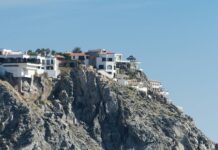 A luxury house on a cliff overlooks the Pacific ocean.