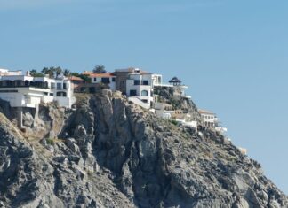 A luxury house on a cliff overlooks the Pacific ocean.