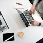 A person sitting at a desk with a laptop and coffee