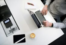 A person sitting at a desk with a laptop and coffee