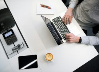 A person sitting at a desk with a laptop and coffee