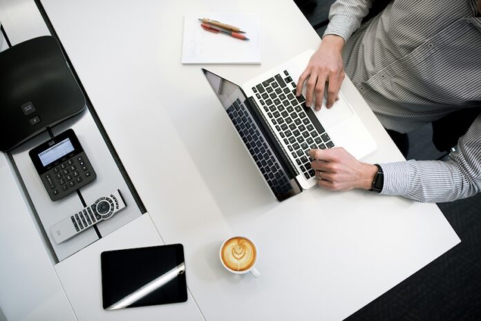 A person sitting at a desk with a laptop and coffee