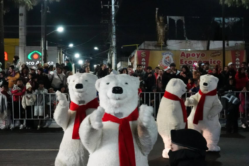 People in Coca-Cola trademarked polar bear costumes dancing in the street as people watch during the brand's annual Christmastime parade in Mexico City.