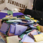 A person dumps a box of votes onto a table
