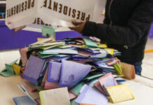 A person dumps a box of votes onto a table