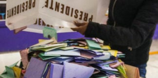 A person dumps a box of votes onto a table