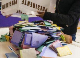 A person dumps a box of votes onto a table