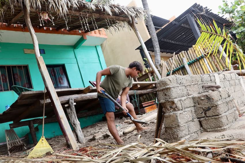 man digging in front of damaged home