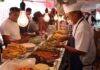 Mexico City residents standing and sitting at a temporary taco stand while waiting for employees to fill their tacos with cooked items in buffet trays.