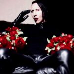 Man with face makeup holding flowers