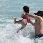 Father and daughter play in surf