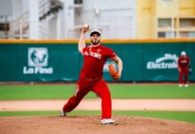 A professional Mexican Baseball League pitcher on the pitching mound, about to pitch a ball during a game in a stadium. He is wearing a El Aguila de Veracruz team uniform.
