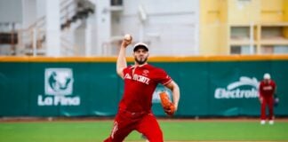 A professional Mexican Baseball League pitcher on the pitching mound, about to pitch a ball during a game in a stadium. He is wearing a El Aguila de Veracruz team uniform.