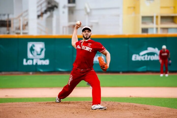 A professional Mexican Baseball League pitcher on the pitching mound, about to pitch a ball during a game in a stadium. He is wearing a El Aguila de Veracruz team uniform.