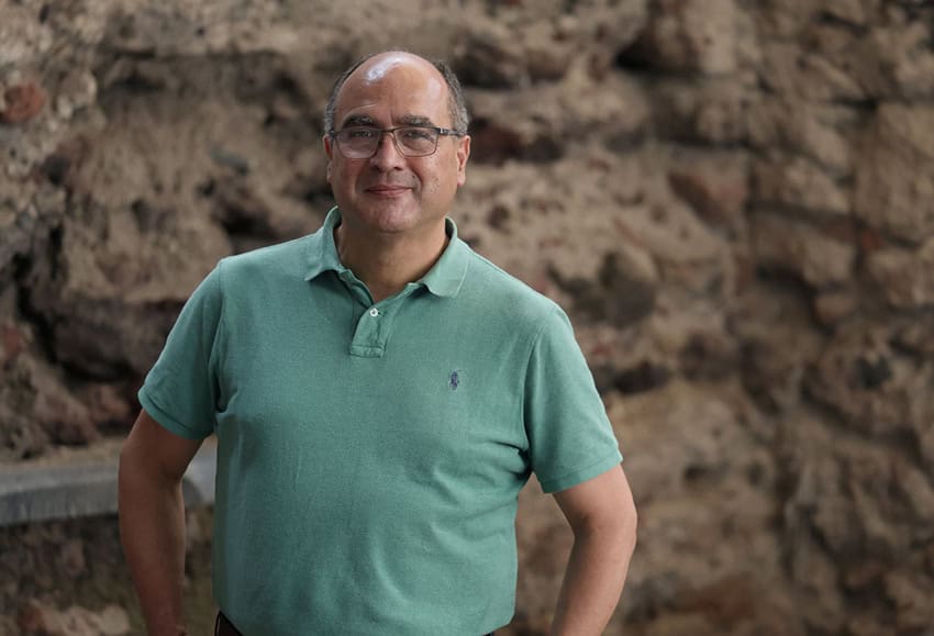 A middle-aged man poses for a photo in an archaeological dig pit