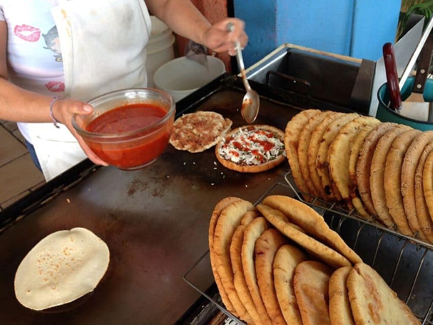 Street vendor prepares fried gorditas on a griddle
