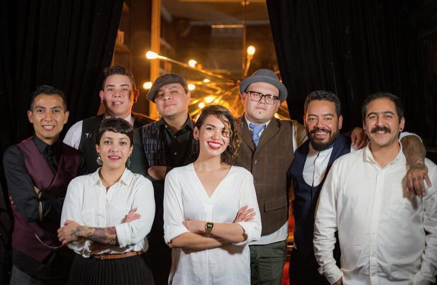 A group of Mexican cocktail bar employees posing in two rows in their high-end bar.