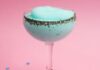 A fluted cocktail glass with a light blue frozen cocktail