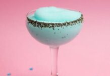 A fluted cocktail glass with a light blue frozen cocktail