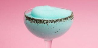 A fluted cocktail glass with a light blue frozen cocktail
