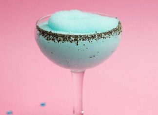 A fluted cocktail glass with a light blue frozen cocktail