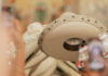 Close-up of a line of white leather Mexican sombreros, all decorated similiarly on the rims with beads and embroidery.