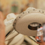 Close-up of a line of white leather Mexican sombreros, all decorated similiarly on the rims with beads and embroidery.