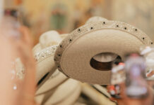 Close-up of a line of white leather Mexican sombreros, all decorated similiarly on the rims with beads and embroidery.