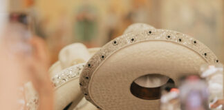 Close-up of a line of white leather Mexican sombreros, all decorated similiarly on the rims with beads and embroidery.