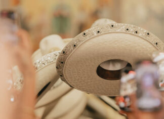 Close-up of a line of white leather Mexican sombreros, all decorated similiarly on the rims with beads and embroidery.