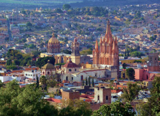 Aerial view of San Miguel de Allende, Mexico, with colonial architecture dominated by tall church steeples and Moorish-style Spanish domed cupolas dotting the skyline.