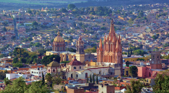 Aerial view of San Miguel de Allende, Mexico, with colonial architecture dominated by tall church steeples and Moorish-style Spanish domed cupolas dotting the skyline.
