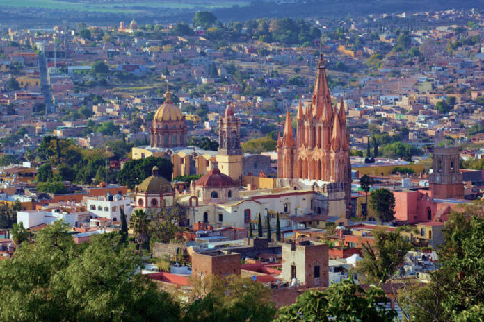 Aerial view of San Miguel de Allende, Mexico, with colonial architecture dominated by tall church steeples and Moorish-style Spanish domed cupolas dotting the skyline.