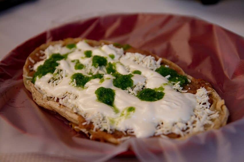 Close up of a sope on a plate topped with cream and green sauce