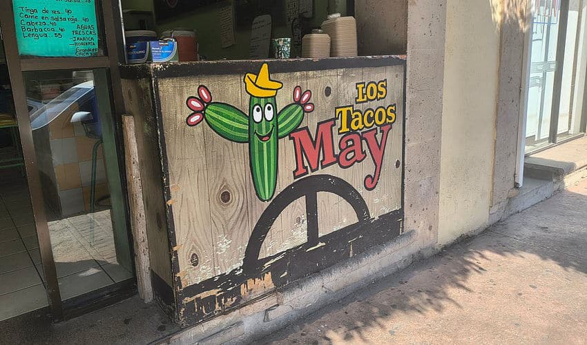 A taqueria sign that features a saguaro cartoon cactus with eyes and a smile and a Mexican-style paisano hat.
