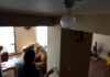 A person touches a light switch during a power outage, while a light bulb remains off in the foreground