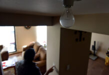 A person touches a light switch during a power outage, while a light bulb remains off in the foreground