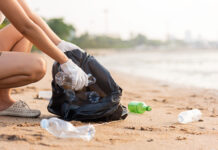 A woman picks up plastic bottles on a beach