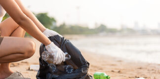 A woman picks up plastic bottles on a beach