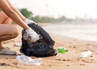 A woman picks up plastic bottles on a beach