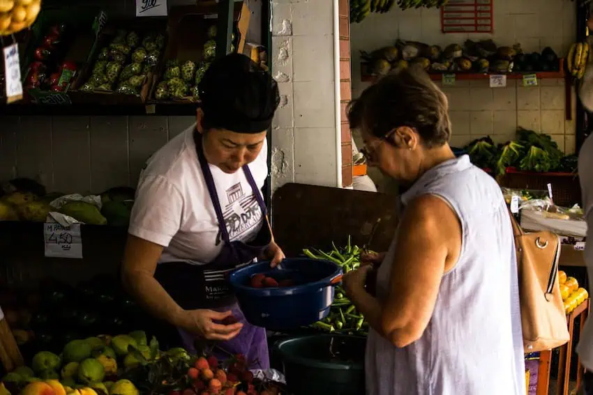 Two women look at groceries at a public market