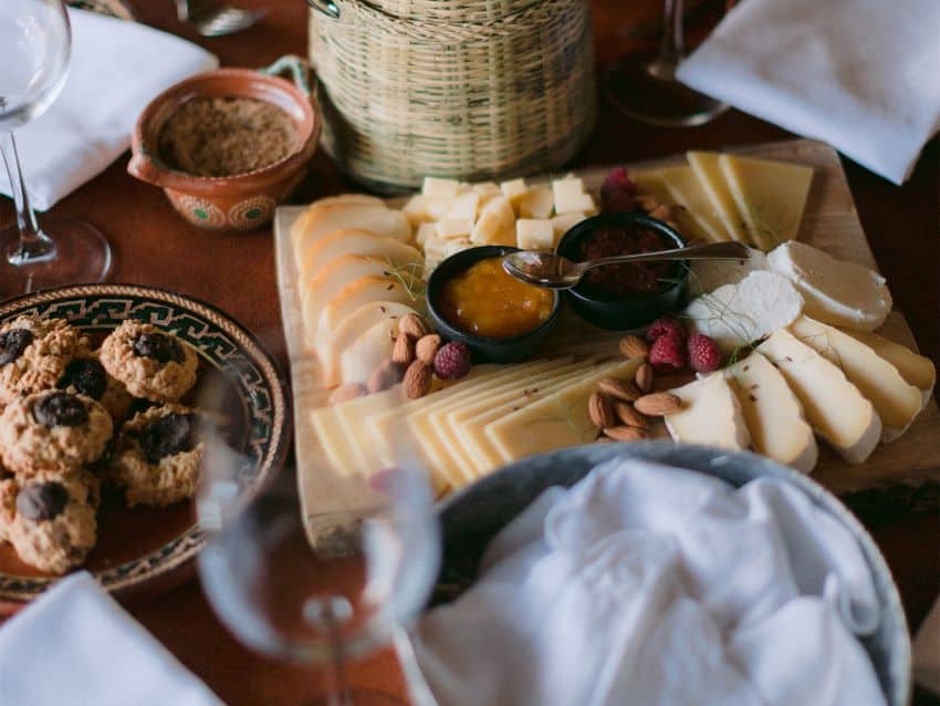 Platter of cheese on a table surrounded by dishes and wine glasses