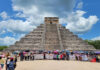Teachers with protest signs and flags gather at the base of the Chichén Itzá pyramid