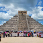 Teachers with protest signs and flags gather at the base of the Chichén Itzá pyramid