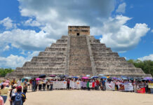 Teachers with protest signs and flags gather at the base of the Chichén Itzá pyramid